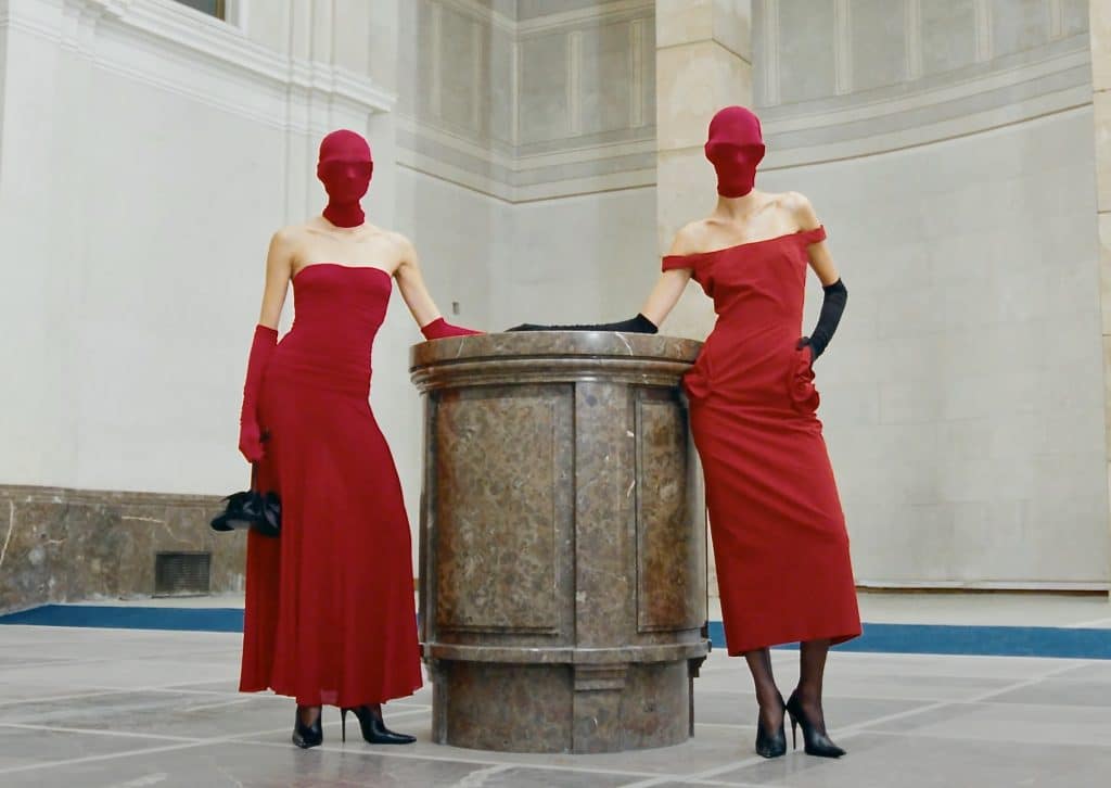 two models in red dresses with red masks at Paris fashion week 2024